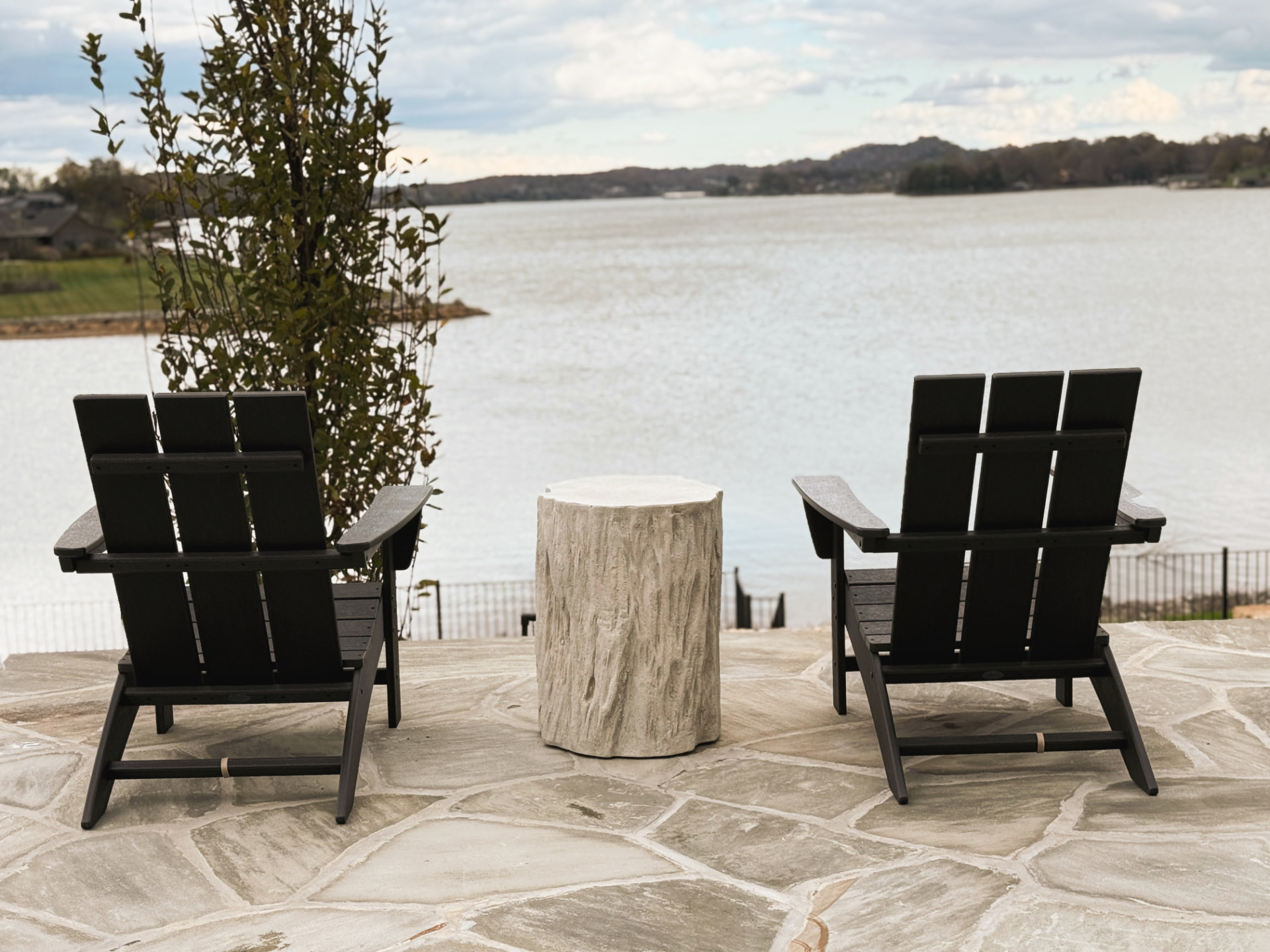 Lakeside terrace with black Adirondack chairs overlooking the water
