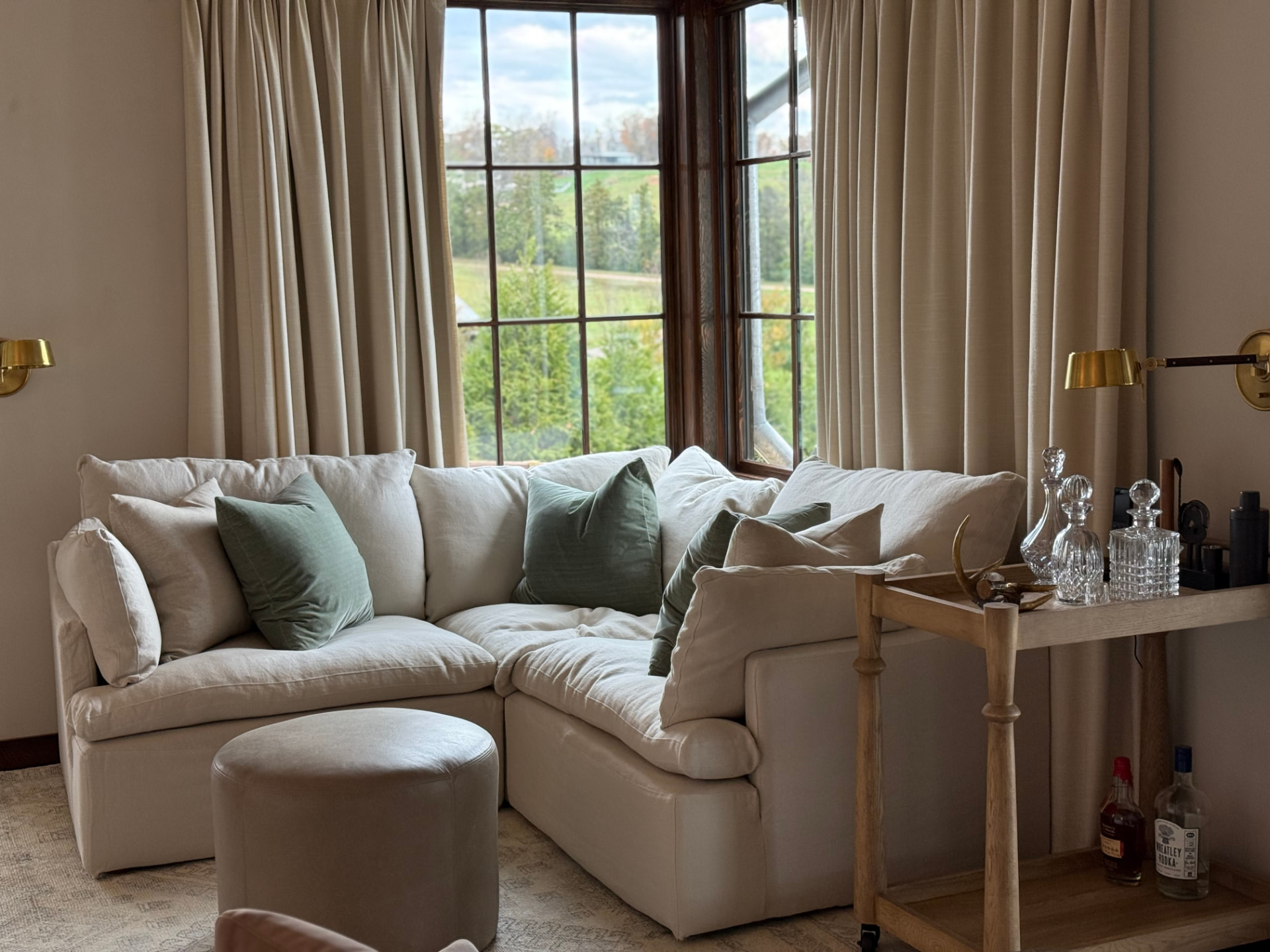 Linen sectional and bar cart installed in a bay-window sitting room